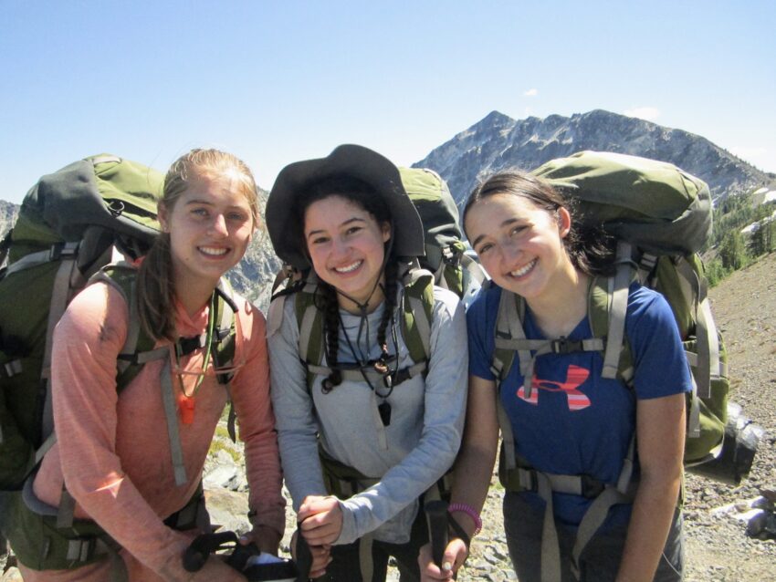 Three Outward Bound students wearing backpacks and standing in front of mountains in the North Cascades.